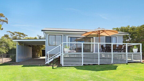 A two-story house with a covered patio area, a staircase leading to the upper floor, and a fenced yard. - Scenic Shack - 4 Scenic Way (CARRICKALINGA)