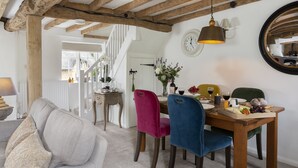 A dining area with wooden beams, a chandelier, and a table set for a meal. - Attractive thatched roof property in the idyllic Cotswold village of Ebrington. (Ebrington, near Chipping Campden)