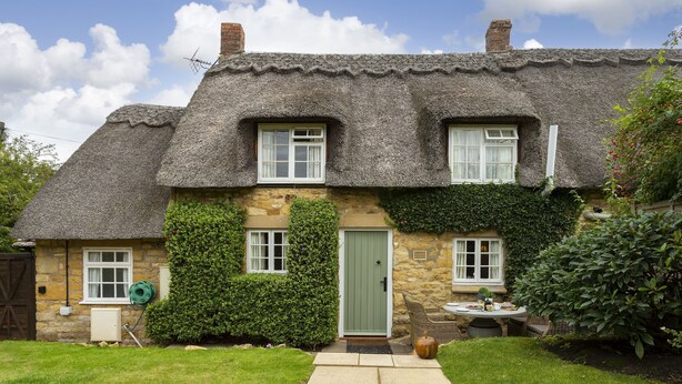 A stone cottage with a thatched roof, a green door, and a small garden. - Attractive thatched roof property in the idyllic Cotswold village of Ebrington. (Ebrington, near Chipping Campden)