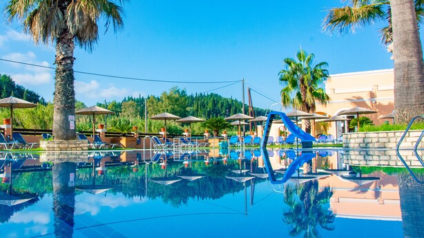 Ein Poolbereich mit Liegestühlen, Sonnenschirmen und Palmen.