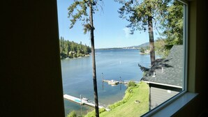 A view of a lake with a dock and boats, surrounded by trees and a grassy area. - Kidd Island (CDA) Lakefront Beauty-Amazing views! (Coeur d'Alene)