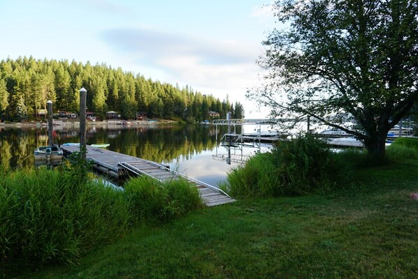 A lakeside dock with boats, a wooden pier, and a forested shoreline.