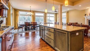 A spacious kitchen with a central island, wooden flooring, and pendant lighting. - Kidd Island (CDA) Lakefront Beauty-Amazing views! (Coeur d'Alene)