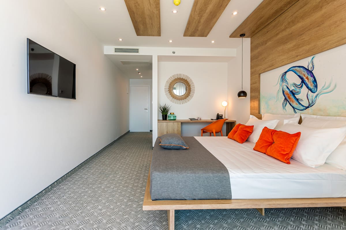 Ein modernes Hotelzimmer mit einem großen Bett, einem Schreibtisch und einem Spiegel.