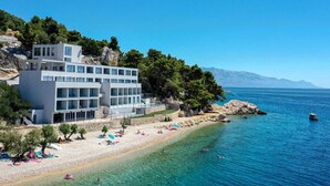 Un hotel moderno con varios pisos, una playa y aguas azules cristalinas.