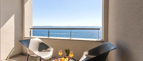 A balcony with a table set for breakfast, two chairs, and a view of the sea.
