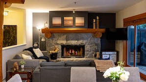 A cozy living room with a stone fireplace, a sofa, a coffee table, and a television.
