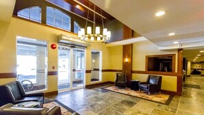 Eine Hotelhalle mit hoher Decke, einem Chandelier, einer Rezeption und einer Sitzecke mit Ledersesseln.