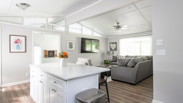 A modern kitchen with white cabinetry, a central island, and a stainless steel trash can.