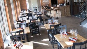 A restaurant with multiple tables and chairs, a bar area, and a staircase.
