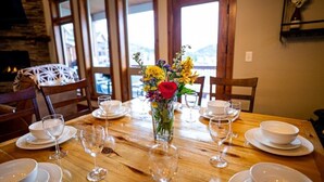 A dining table set with white plates, bowls, and wine glasses, centered with a vase of flowers. - Mountain Views, Close to RMNP Entrance, Hot Tub! Casa Kiowa, Estes Park CO (Estes Park)