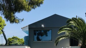 A modern two-story house with a large window, a staircase, and a well-maintained lawn. - Villa   Tranquility. (Athens)