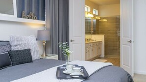 Une chambre à coucher avec un lit, une table de chevet, une lampe et un plateau avec des tasses et des soucoupes.