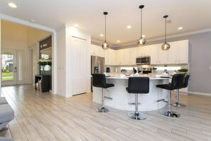 A modern kitchen with white cabinets, stainless steel appliances, and a central island with bar stools.