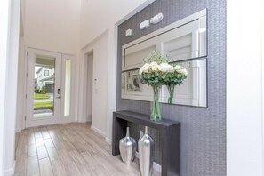 A hallway with a modern console table, a mirror, and a vase with flowers.