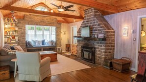 A cozy living room with a stone fireplace, wooden beams, and a comfortable seating area. - 5 Bed Cottage & 2 Bunkies! Boathouse Rooftop Deck with Sunsets! (Muskoka Lakes)