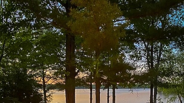 A deck with a fire feature, seating, and a view of a lake. - 5 Bed Cottage & 2 Bunkies! Boathouse Rooftop Deck with Sunsets! (Muskoka Lakes)