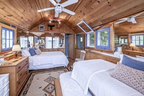 A cabin with two bedrooms, each with a bed, a dresser, and a nightstand. There is a ceiling fan in the center of the room. - 5 Bed Cottage & 2 Bunkies! Boathouse Rooftop Deck with Sunsets! (Muskoka Lakes)