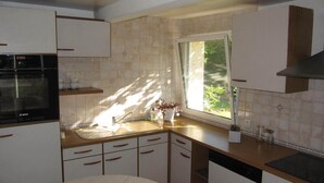 Una cocina con horno Bosch, un lavabo y una ventana que da a zonas verdes.