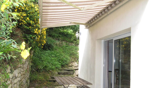 Un patio con dos bancos de madera, un muro de piedra y un ventanal de vidrio que da a un jardín.