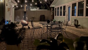 Patio esterno con borsa, sedie in metallo e luci a catena.