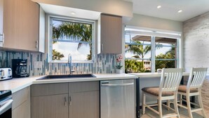 A modern kitchen with a large window, a coffee maker, and a sink.
