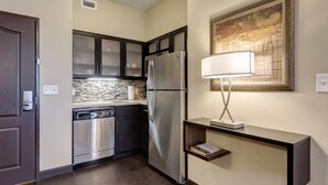 A compact kitchen with dark cabinets, stainless steel appliances, and a modern light fixture. - Free Breakfast + Gym, and BBQ Area! Studio Suite Perfect for Business Travelers (Maryland Heights)