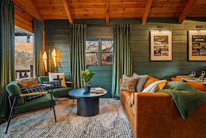 A cozy room with a green sofa, a wooden table, and a view of a building outside.