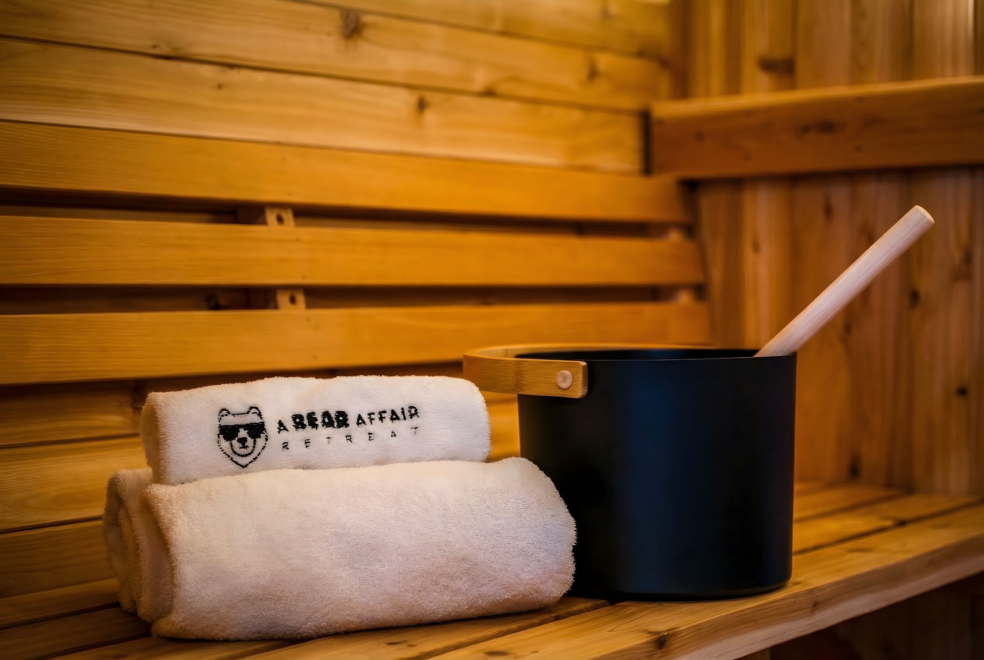Un banco de madera con una toalla y un recipiente negro con asa de madera.