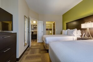 Ein Hotelzimmer mit zwei Betten, einem Fernseher, einem Kleiderschrank und einem durch eine offene Tür einsehbaren Badezimmer.