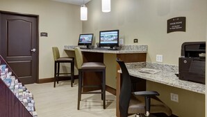 Een hotel receptie met twee computers, een printer en een bureau met stoelen.