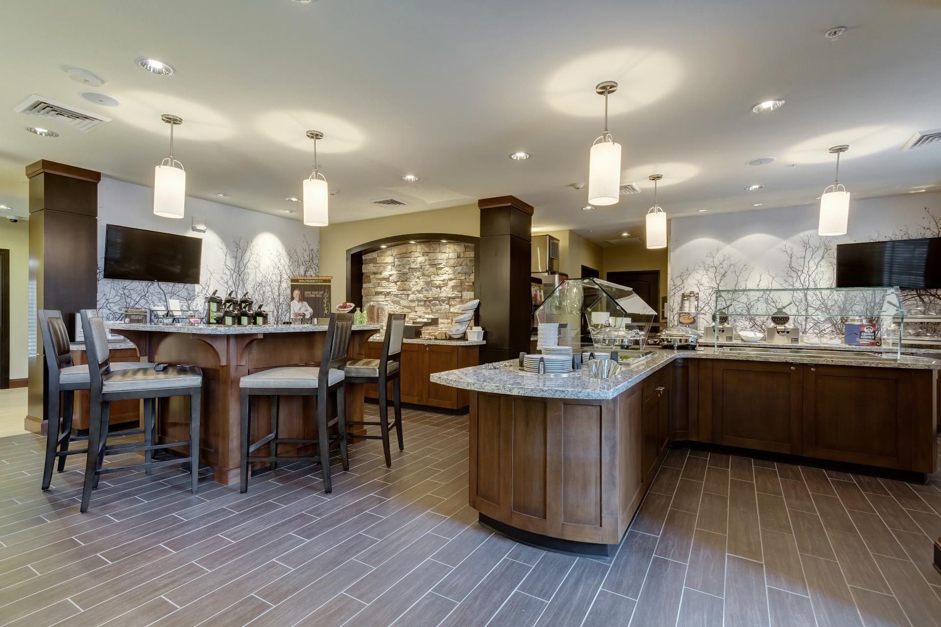 Una cocina moderna con encimera de mármol, armarios de madera y una pared decorativa de piedra.