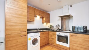 Een moderne keuken met houten kastjes, een ingebouwde wasmachine en een fornuis.