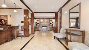 A hotel lobby with a fireplace, seating area, and a reception desk.