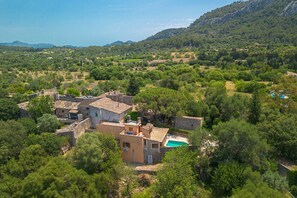 Eine ländliche Villa mit Swimmingpool, umgeben von üppiger Vegetation und Hügeln.