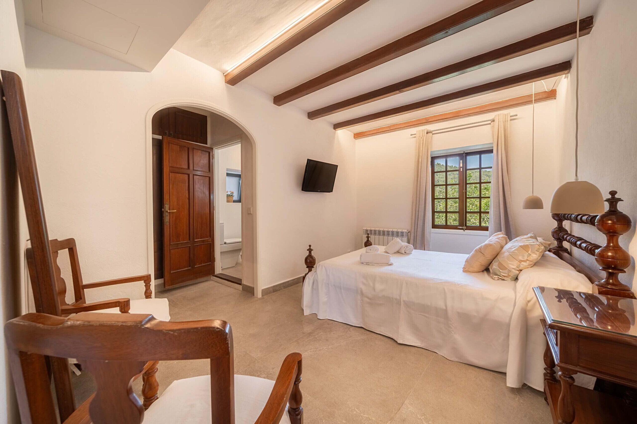 Une chambre à coucher avec un lit, des meubles en bois, une télévision et une fenêtre avec des rideaux.