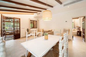 Une pièce spacieuse avec une grande table à manger, un canapé et un luminaire suspendu.