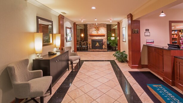 A hotel lobby with a reception desk, seating area, and a fireplace.