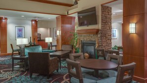 A hotel lobby with a fireplace, seating area, and a television mounted on the wall.