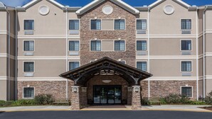 A multi-story hotel with a stone facade, a central entrance with a wooden arch, and multiple windows on each floor. - Relaxing retreat in Tallahassee! Free Breakfast + On-Site Business Center (Tallahassee)