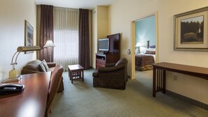 A hotel room with a wooden desk, a brown armchair, a television, a bed with a patterned bedspread, and a framed picture on the wall. - Relaxing retreat in Tallahassee! Free Breakfast + On-Site Business Center (Tallahassee)