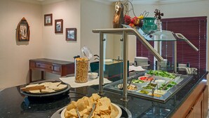 A buffet setup with various food items, a clock on the wall, and a decorative windmill. - Relaxing retreat in Tallahassee! Free Breakfast + On-Site Business Center (Tallahassee)