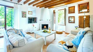 A cozy living room with a fireplace, comfortable seating, and a view of the outdoors.
