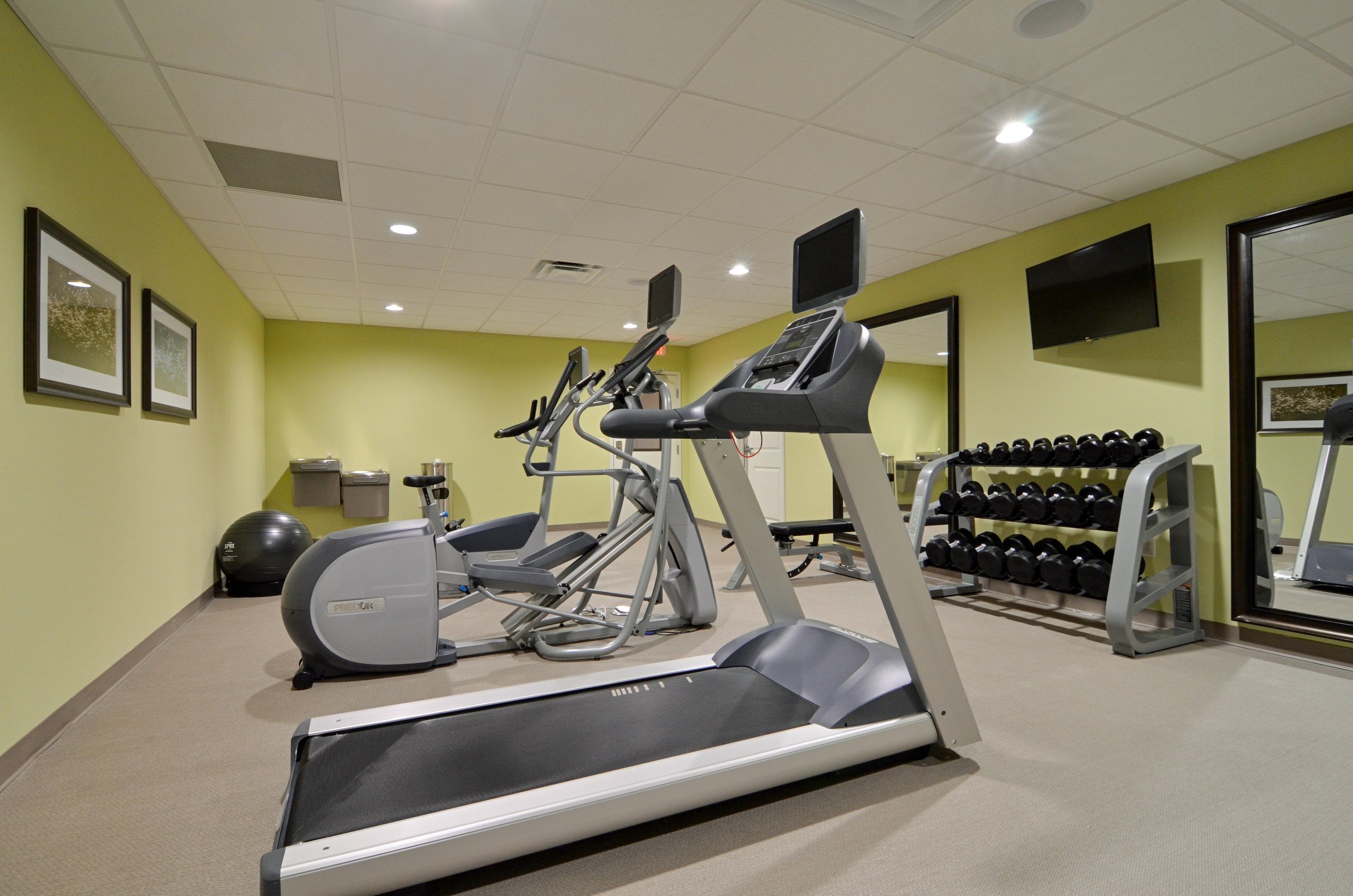 Une salle de sport équipée de tapis de course, d’un vélo elliptique, d’un vélo d’appartement et d’un porte-haltères.