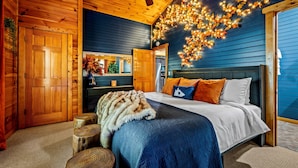 Een knus houten slaapkamer met een bed, houten wanden en een plafondventilator.