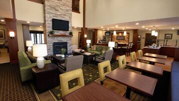 A hotel lobby with a fireplace, seating area, and a bar.