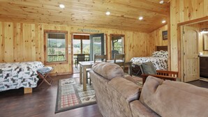 A log cabin with two bedrooms, a dining area, and a living room with a sofa.