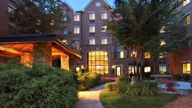 A multi-story brick building with a central courtyard, stone pillars, and a large glass window. - Studio Suite with Private Patio! Free Breakfast + On-Site Business Center (McLean)