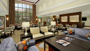 A spacious lobby with multiple seating areas, including sofas and chairs, and a large window providing natural light.