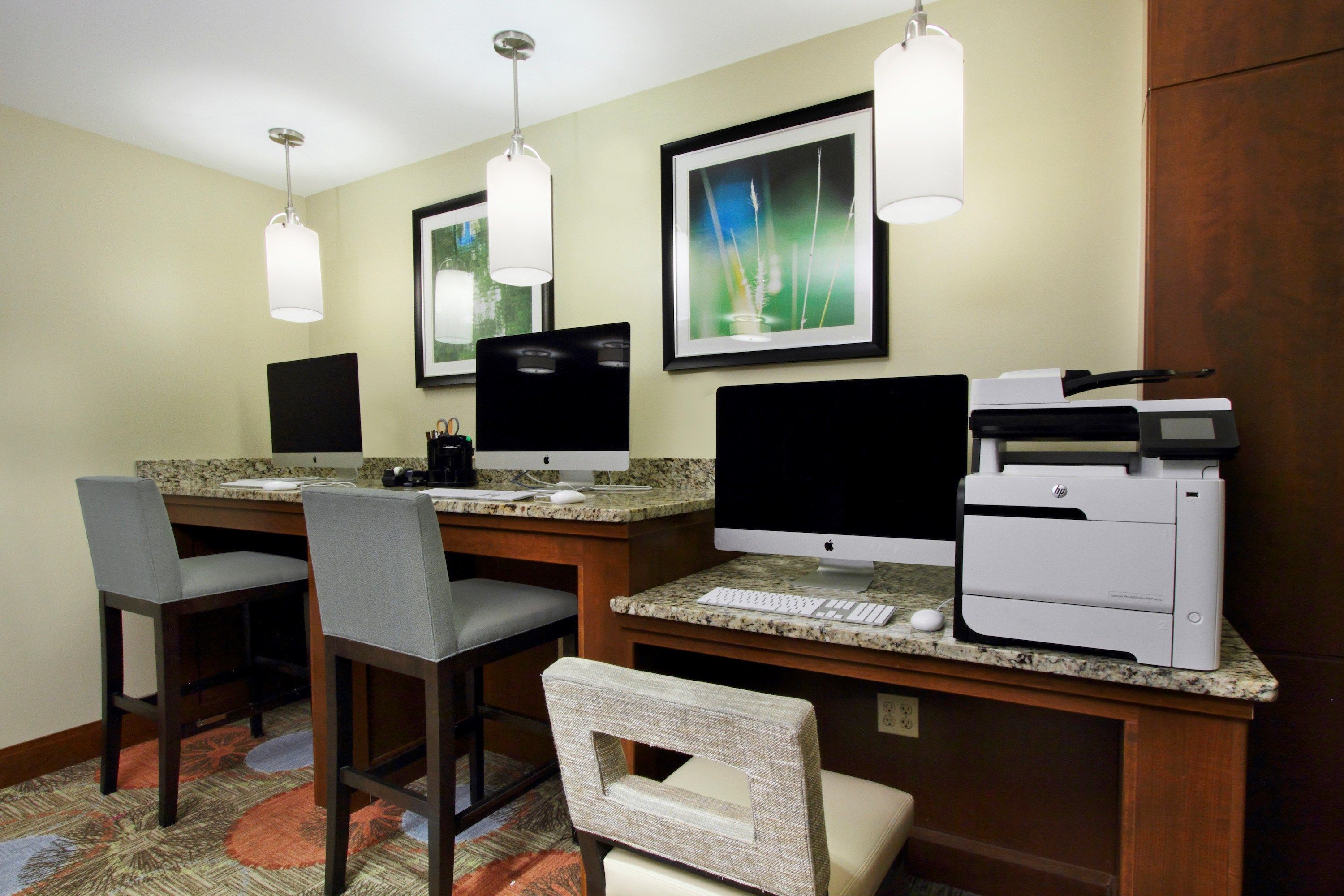 A hotel workspace with two desks, computers, and a printer.